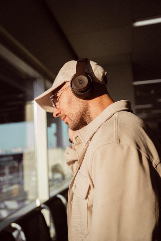 picture of a 30-year-old handsome man wearing a hat and headphones, looking out the window. Image before it is converted to anime-styled image using ControlNet Lineart Anime